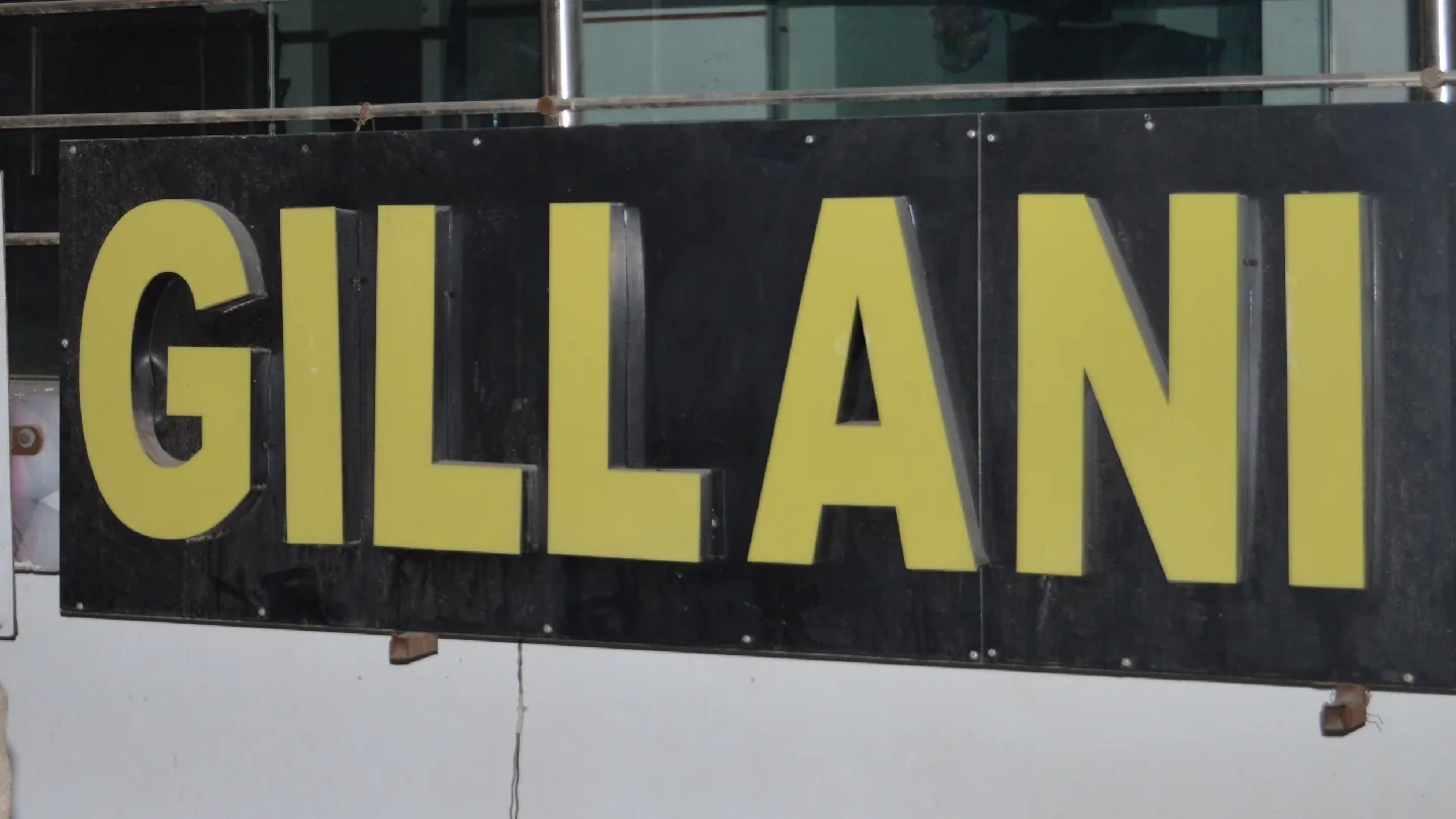 The lit GILLANI sign outside the office